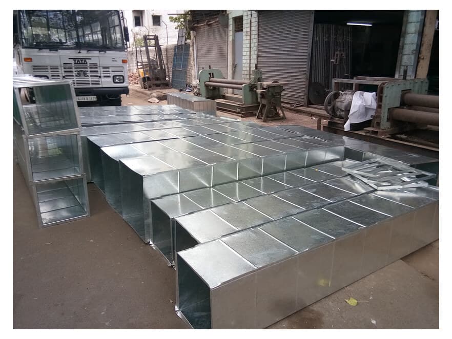 Galvanized rectangular duct sections stacked on the factory floor before dispatch.